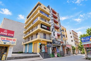 Un hotel de varios pisos con balcones, una tienda a la vista en la planta baja y señalización para un gimnasio y un salón de belleza.