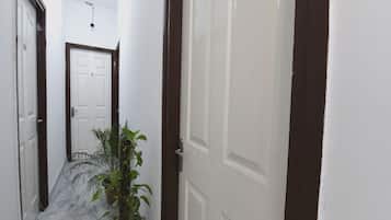 Corredor com planta em vaso, porta branca e placa de número.