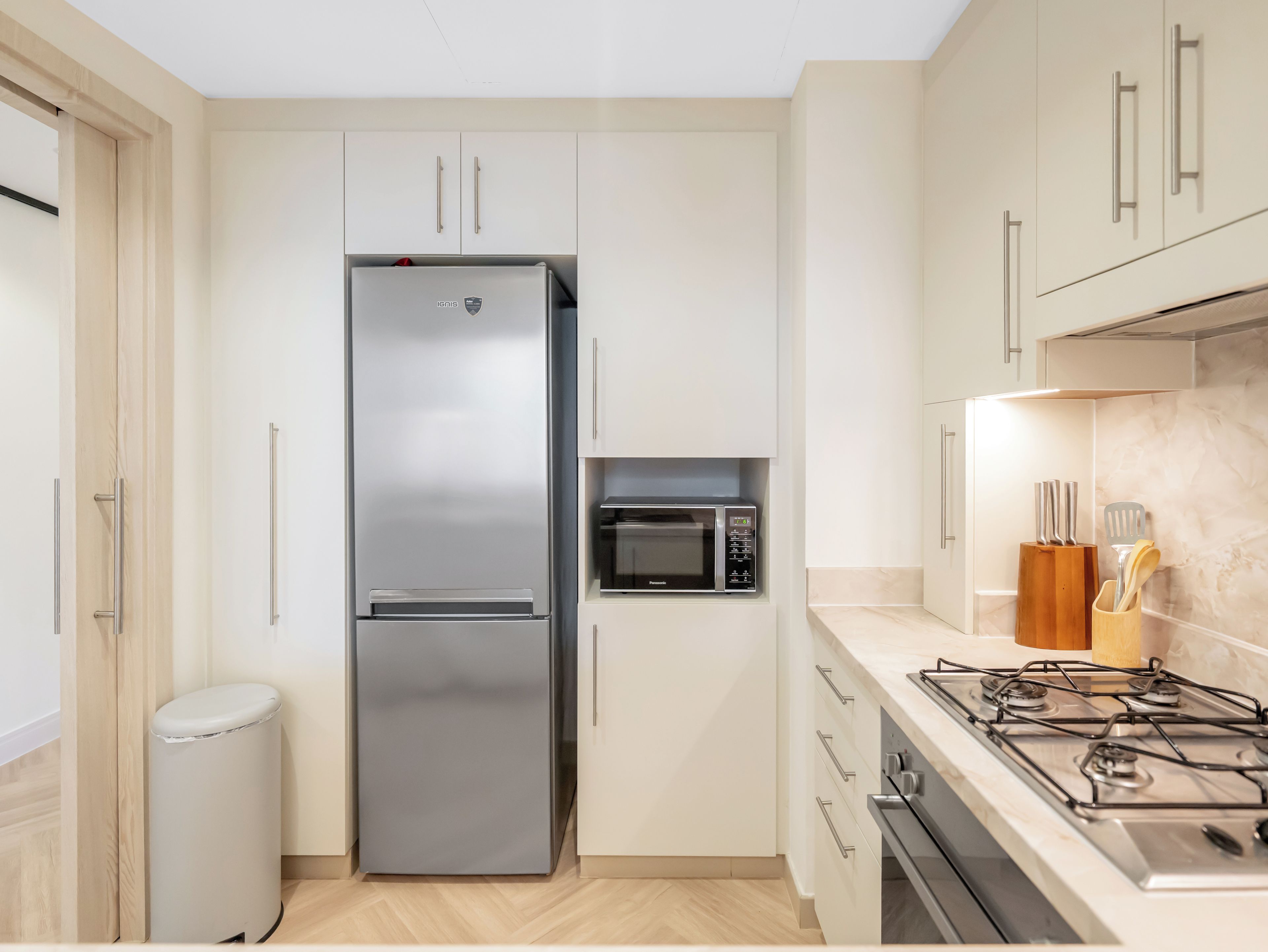 Una cocina con un refrigerador de acero inoxidable, un microondas y una estufa a gas.
