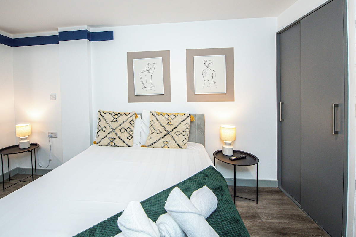 Una habitación de hotel con una cama, dos lámparas de noche, un armario y dos cuadros en la pared.