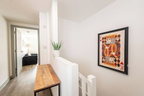 A hallway with a wooden table, a potted plant, and a framed artwork on the wall. - The Roscoe Street Aparts by StaySavvy (Liverpool)