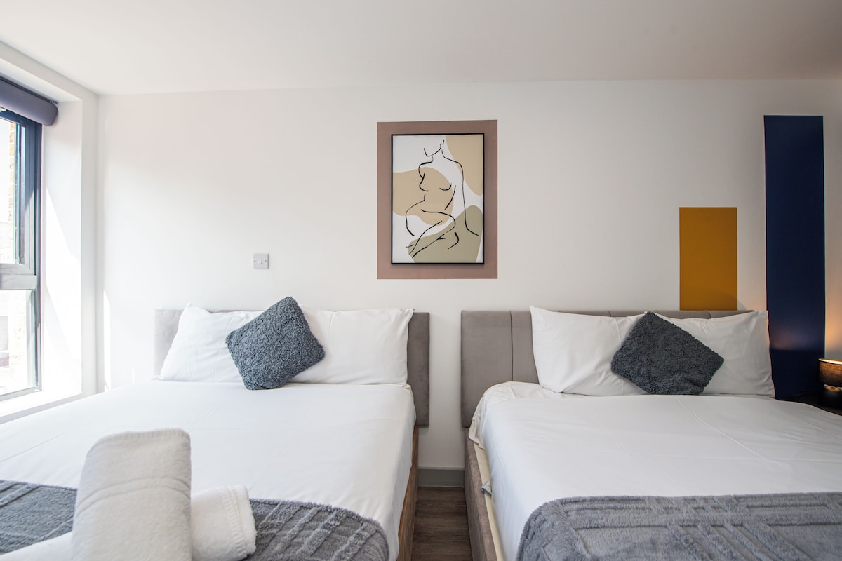 Habitación de hotel con dos camas, una obra de arte enmarcada en la pared y una ventana que proporciona luz natural.