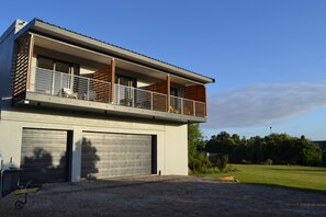 A modern two-story building with a balcony, garage doors, and a paved driveway. - Swanemeer Apartments (Cape Town)