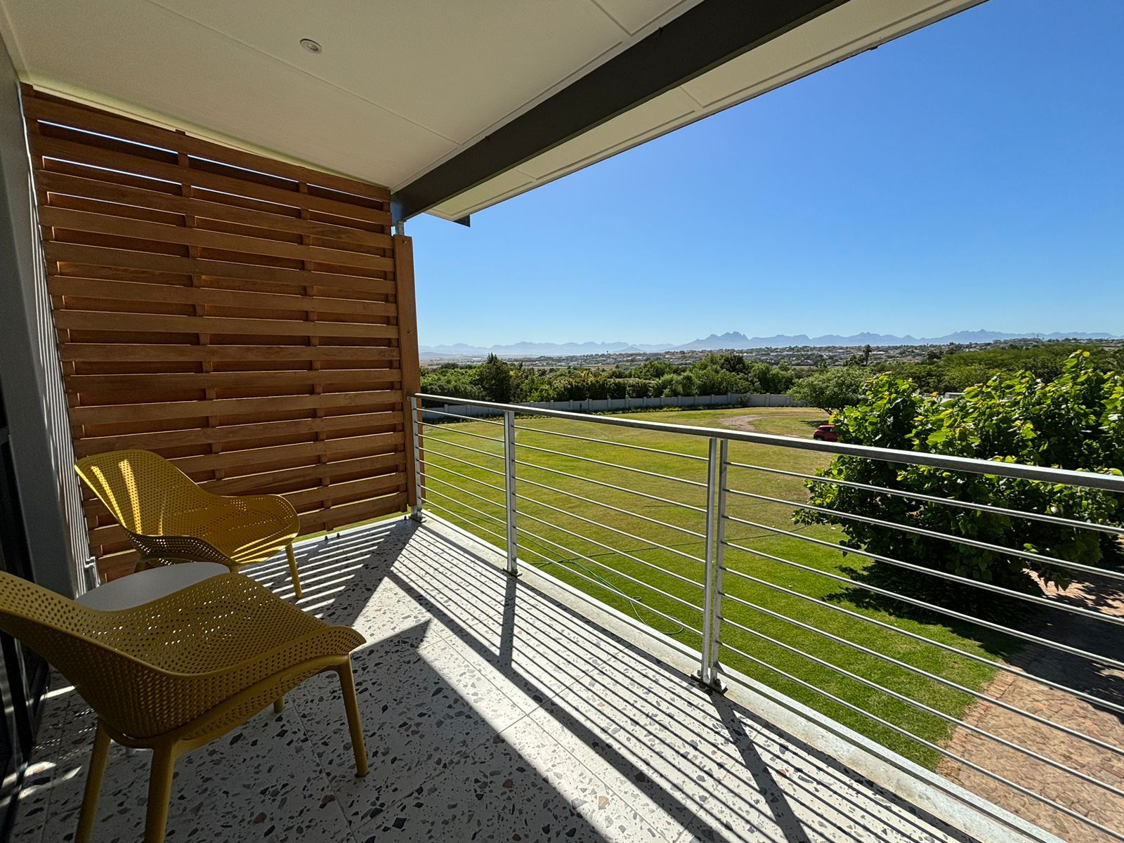 Ein Balkon mit Blick auf eine grüne Landschaft und ferne Berge.