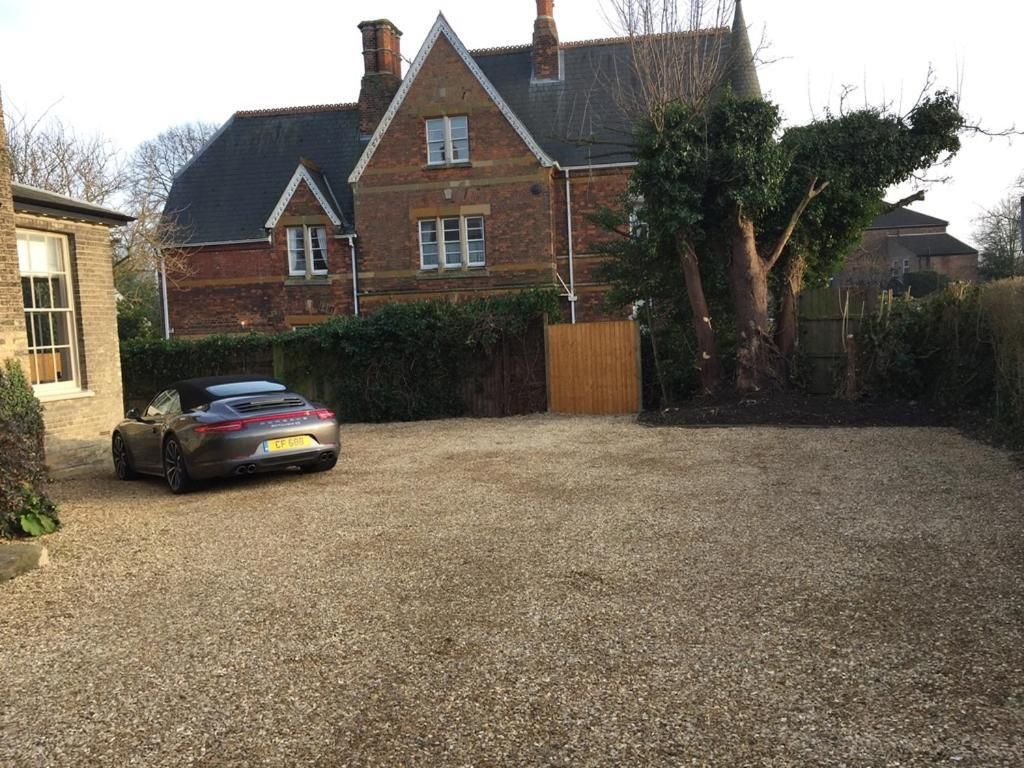 Une allée menant à une maison, avec une voiture garée devant une maison en briques.