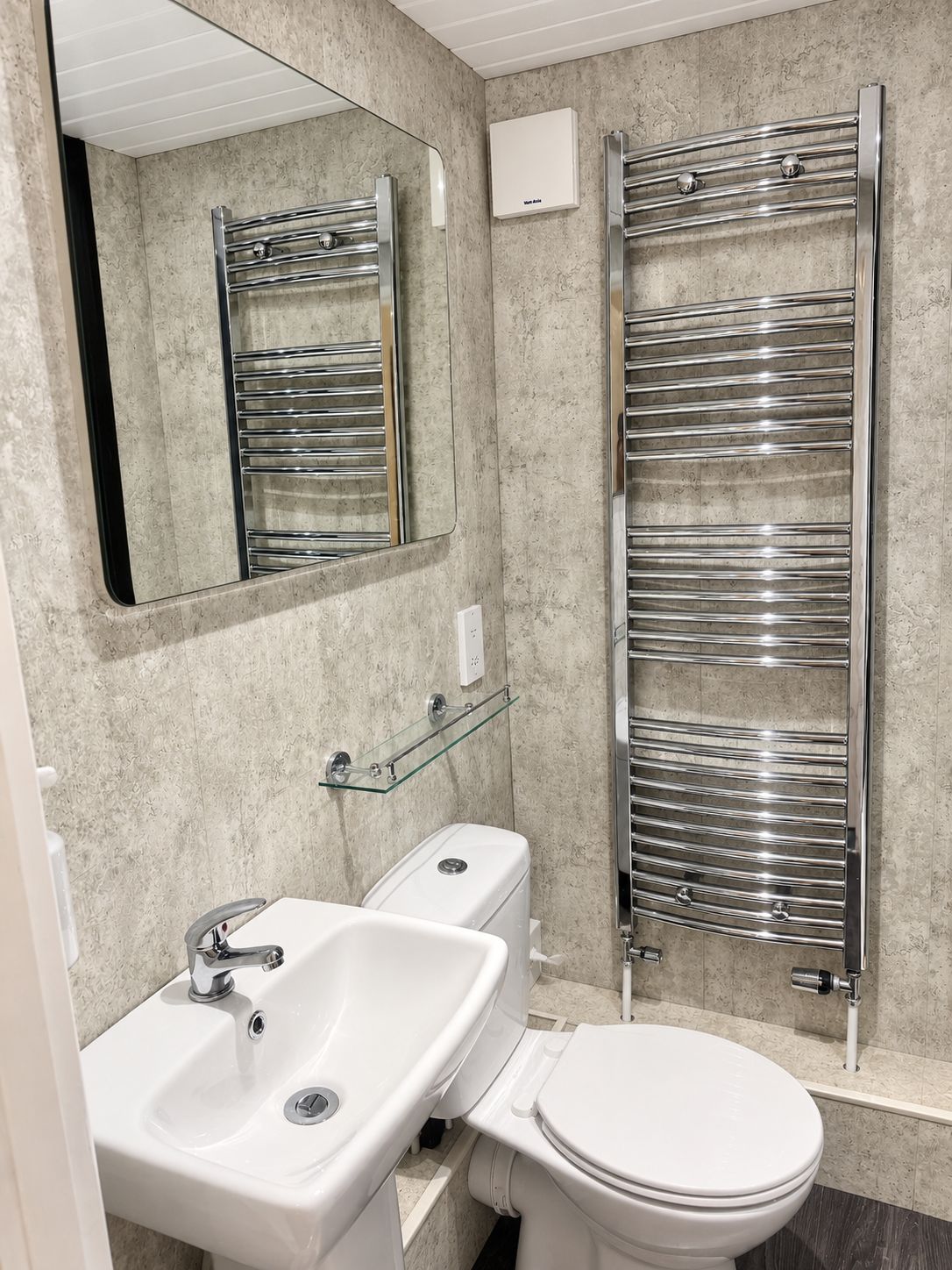 A modern bathroom with a sink, toilet, and a glass shelf.