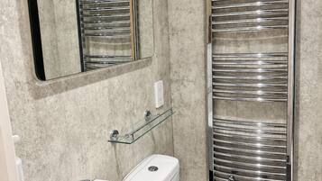 A modern bathroom with a sink, toilet, and a glass shelf.