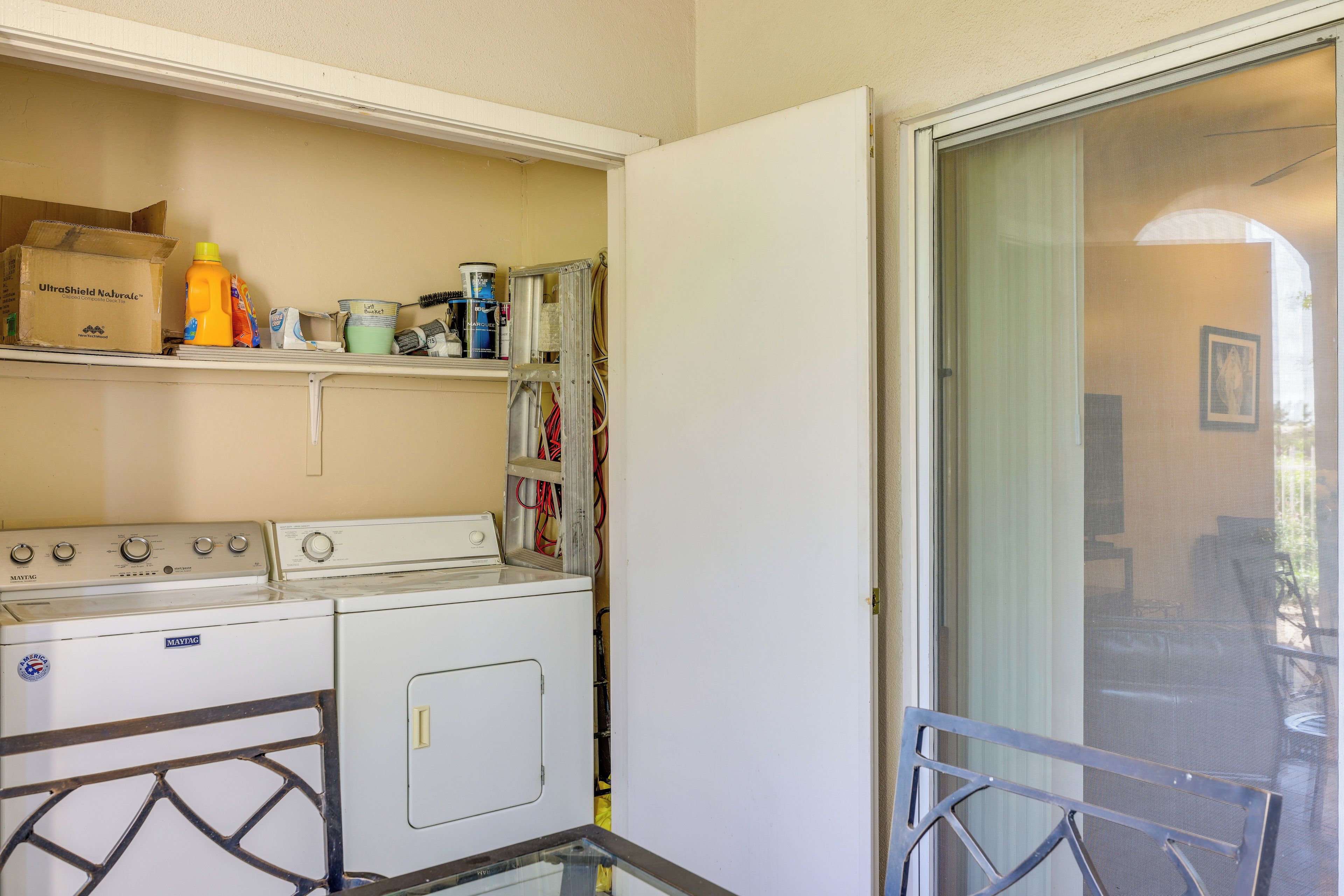 A laundry area with a washing machine, dryer, and shelves with cleaning supplies.