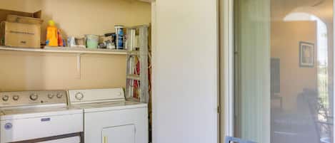 A laundry area with a washing machine, dryer, and shelves with cleaning supplies.