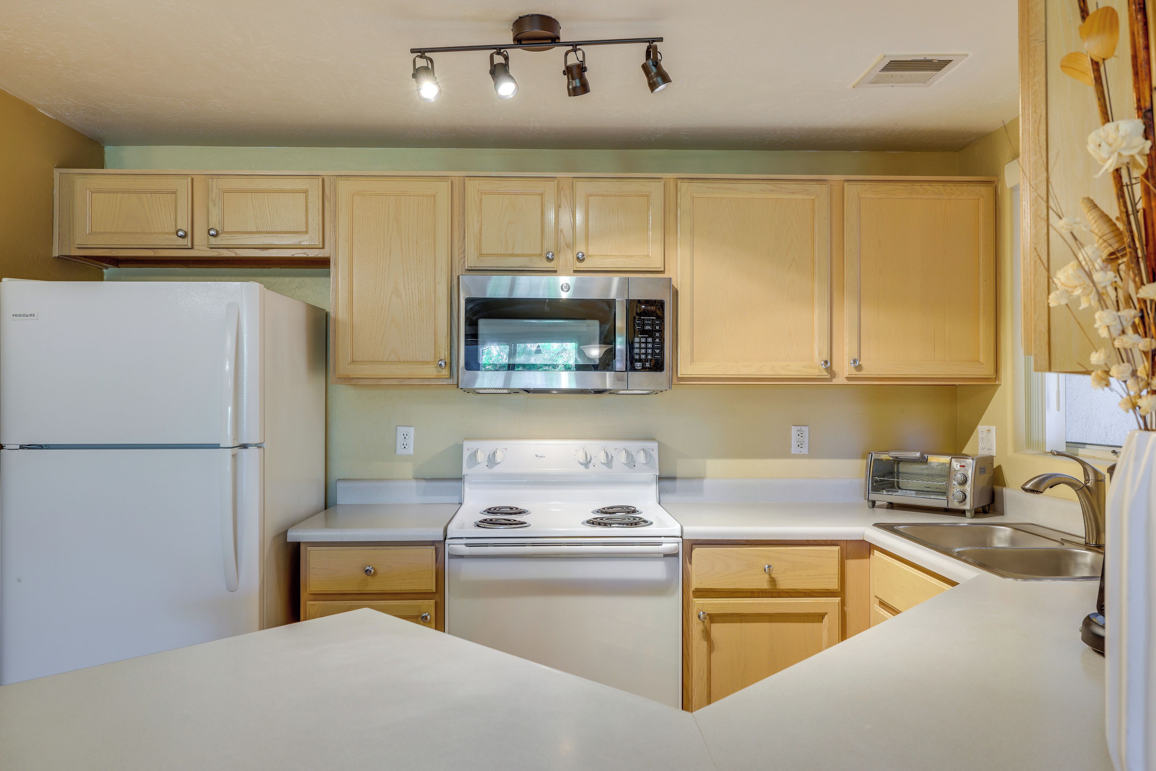 A kitchen with wooden cabinets, a stainless steel microwave, a white stove, and a built-in oven.