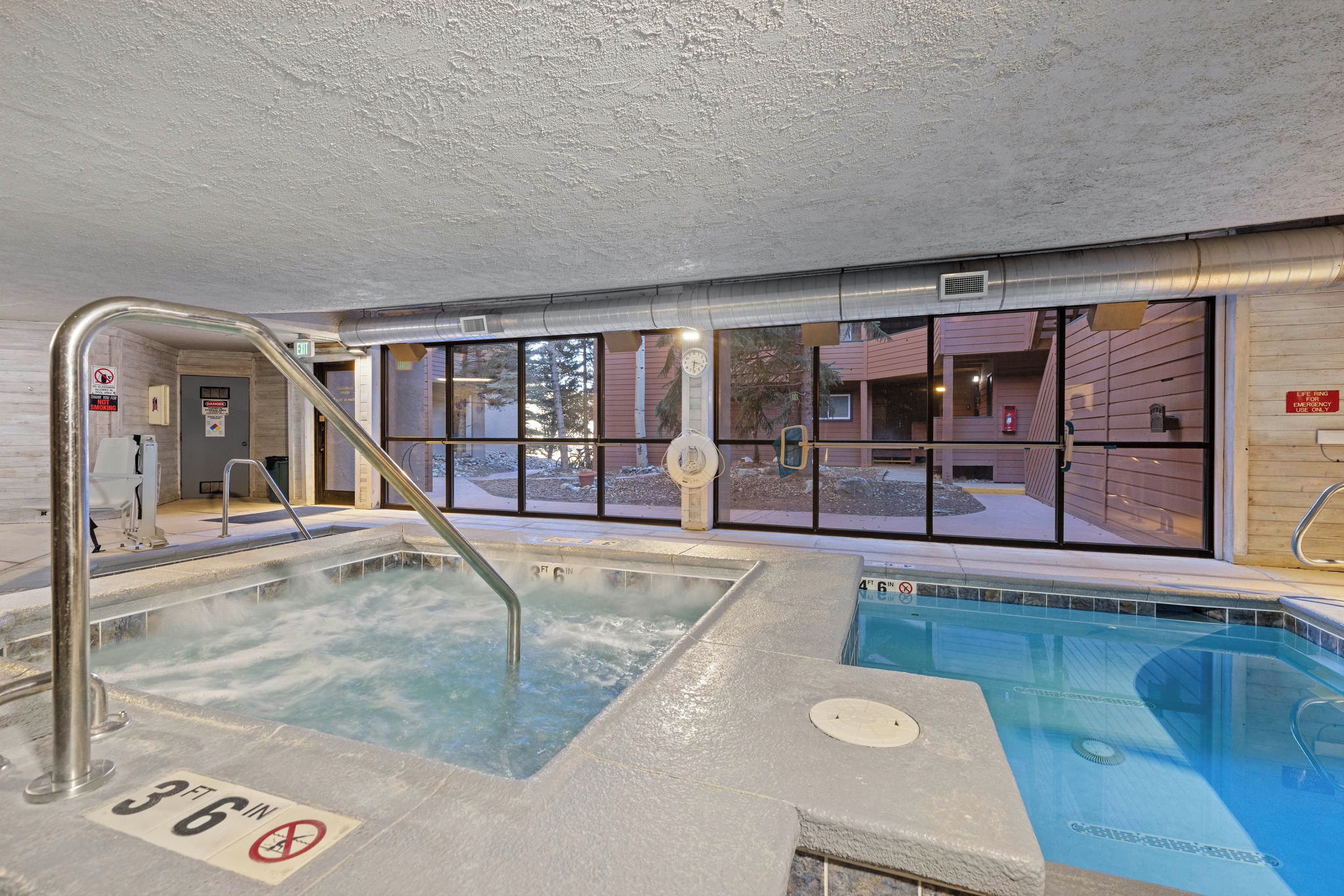 An indoor swimming pool with a 3 ft depth marker, a no smoking sign, and a life ring emergency use sign.