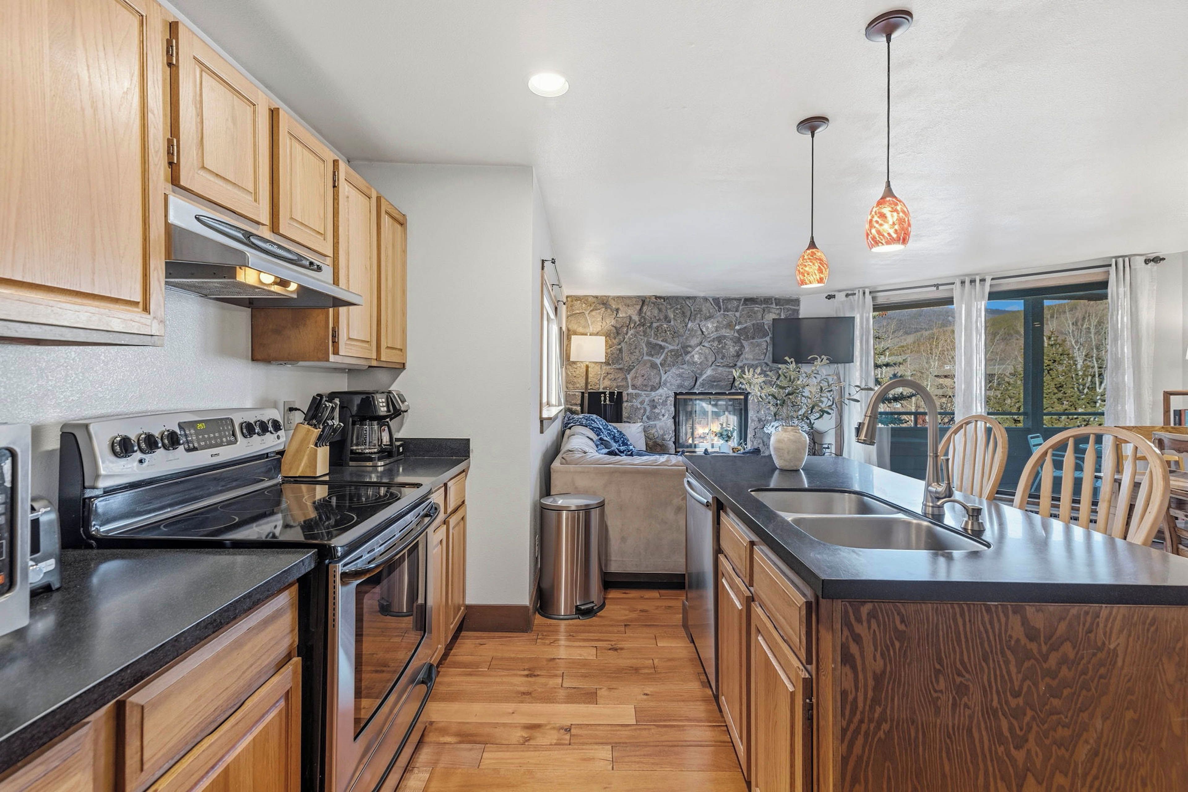 A modern kitchen with wooden cabinets, a stove, and a large island with a sink.