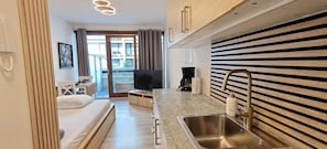 Quarto de hotel compacto com cozinha compacta, cama, televisão e vista para o exterior.