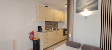 Una cocina compacta con armarios de madera, horno integrado y cafetera.
