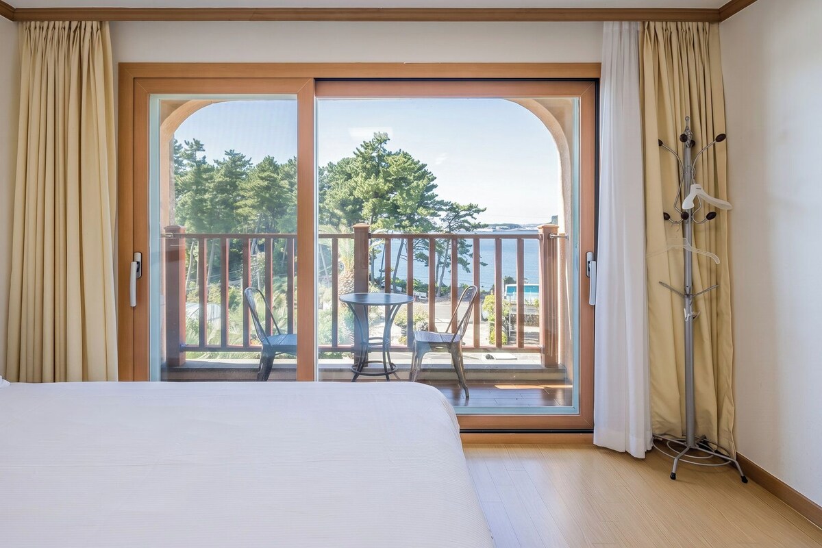 Ein Hotelzimmer mit Bett, einem Balkon mit Tisch und Stühlen sowie einem Kleiderständer.