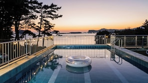 Ein Schwimmbecken mit Blick auf den Sonnenuntergang und Berge im Hintergrund.