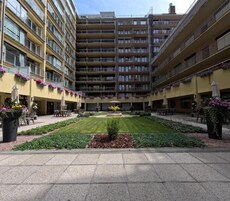 Un patio central con césped, rodeado de edificios de varios pisos con balcones y terrazas.