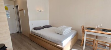 Un dormitorio pequeño y ordenado, con cama, mesita de noche y una silla.