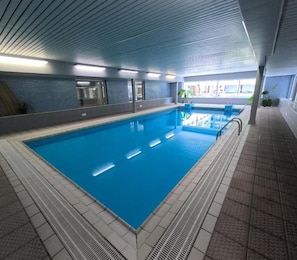 Piscina interna com água cristalina, paredes e piso revestidos em azulejo.