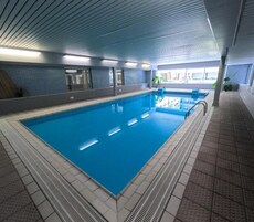 Piscina interna com água cristalina, paredes e piso revestidos em azulejo.