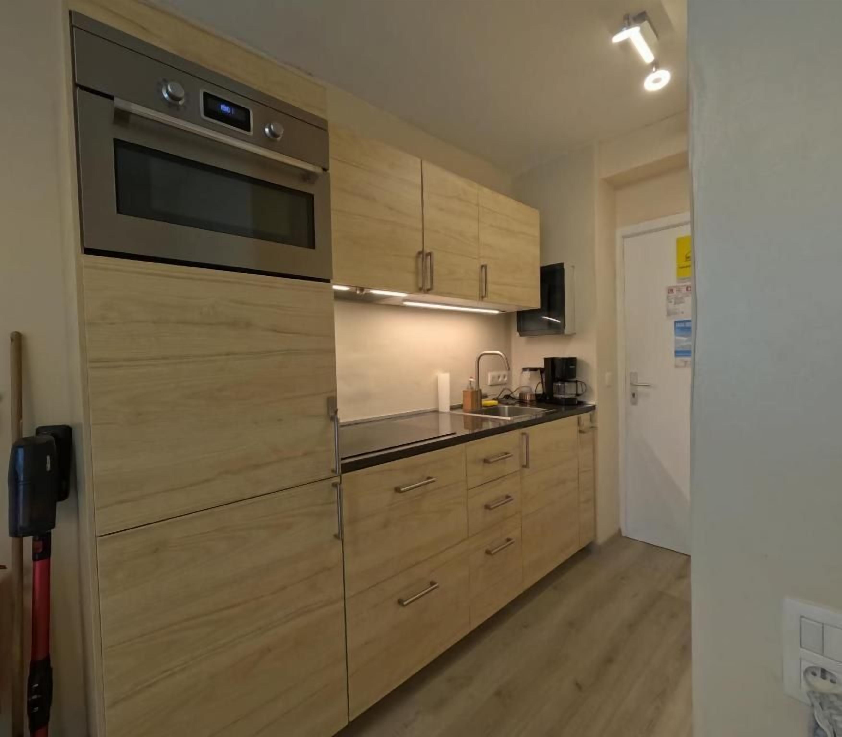 Een keuken met houten kastjes, een inbouwoven en een koffiezetapparaat.