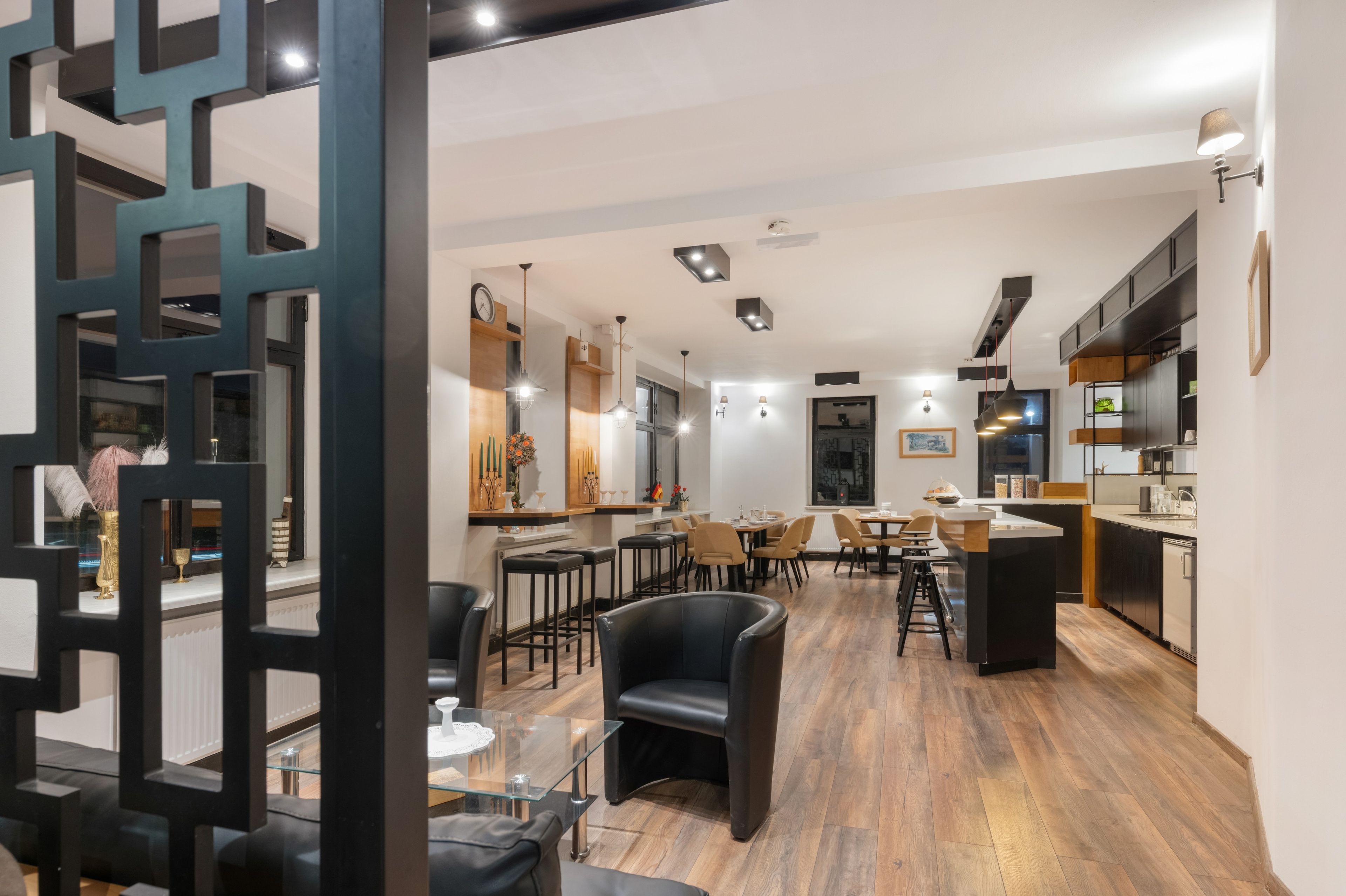 A modern kitchen with a dining area, wooden flooring, and contemporary lighting fixtures.