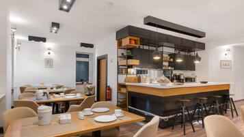 Une cuisine moderne dotée d’un îlot central, de tabourets de bar et d’un coin repas avec des tables et des chaises.