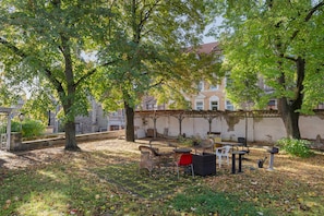 Een binnentuin met terras, bomen en een gebouw op de achtergrond.