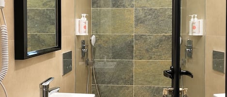 Un baño moderno con ducha envuelta en vidrio, un lavamanos blanco y un inodoro.