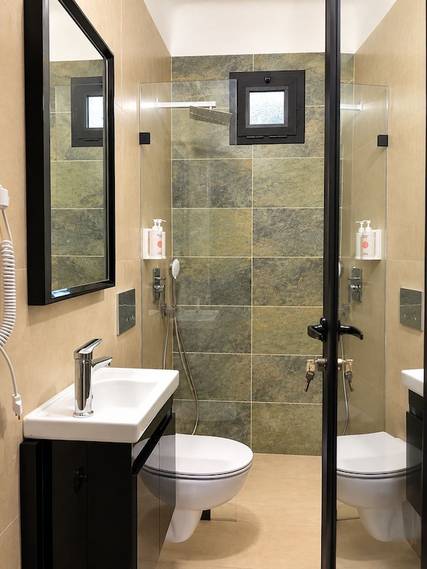 A modern bathroom with a glass-enclosed shower, a white sink, and a toilet. - ACHAKAR32 (Tangier)