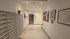 Passadís amb una filera d'armaris metàl·lics a l'esquerra, una porta al final i quadres als murs.