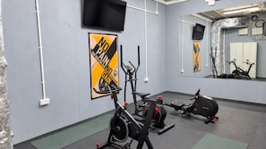 Gimnàs amb equip d'exercici, un pòster motivacional i un mirall que reflecteix l'equipament.