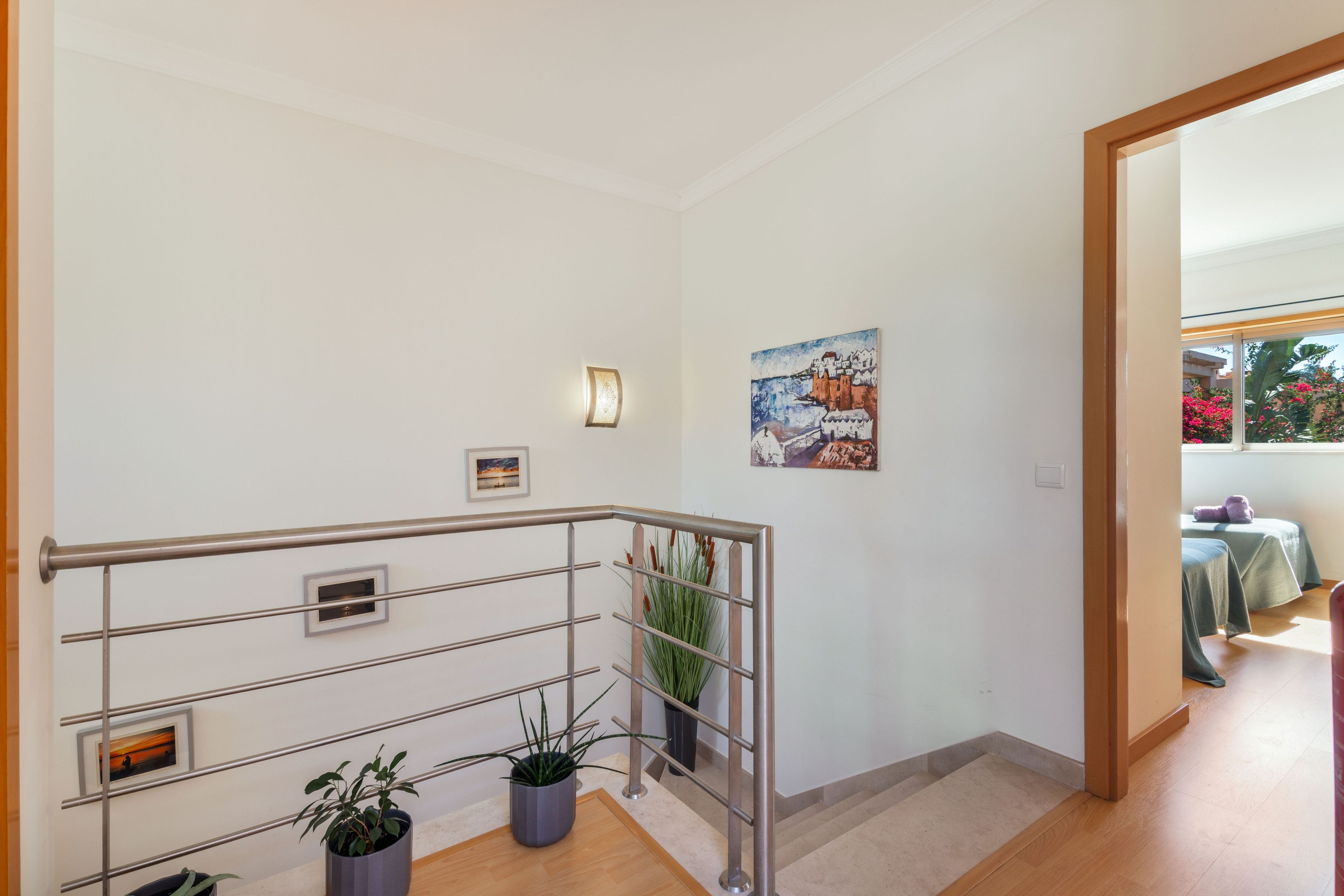 Un escalier avec des rampes en métal, une plante en pot et un tableau accroché au mur.