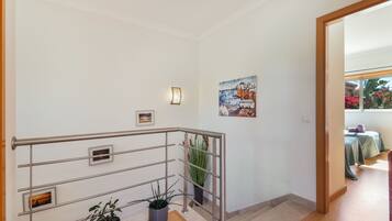 Un escalier avec des rampes en métal, une plante en pot et un tableau accroché au mur.