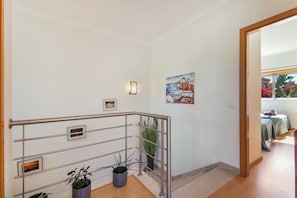 A staircase with metal railings, a potted plant, and a painting on the wall. - Holiday Home 'Villa Quarto Crescente' with Shared Pool, Private Terrace and Air Conditioning (Albufeira)