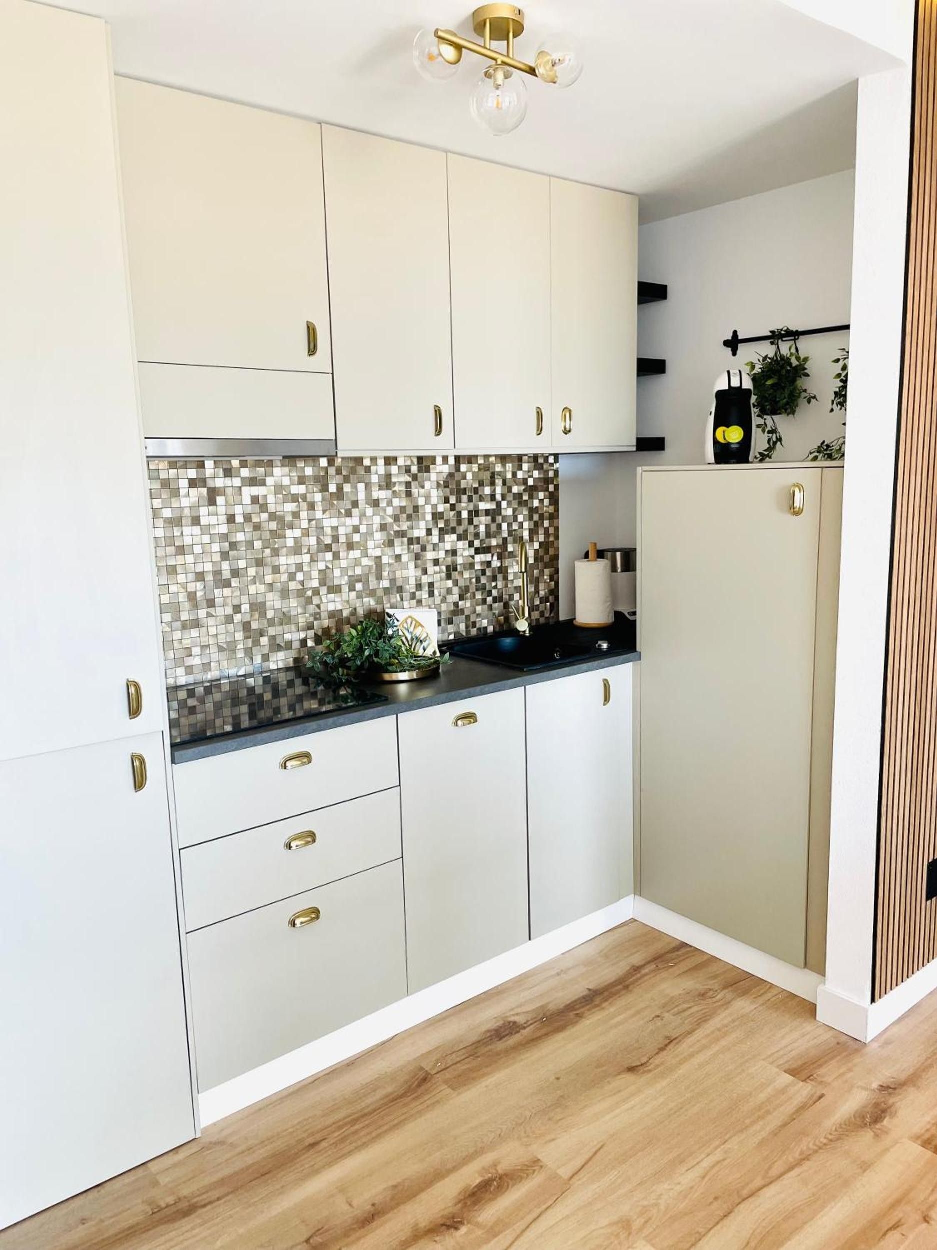 Eine moderne Küche mit weißen Schränken, einer schwarzen Arbeitsplatte und einer Mosaik-Spritzschutzwand.