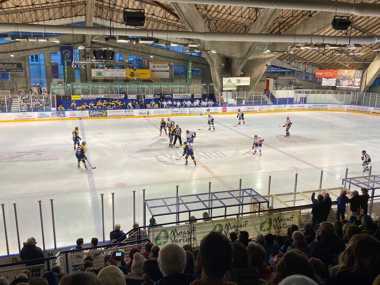 Une patinoire intérieure où se pratique le hockey sur glace, avec des spectateurs assis dans les gradins.