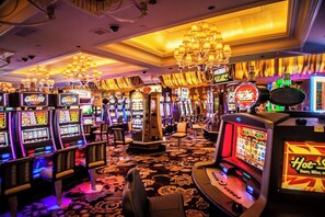 Een casino met veel gokkasten, een kroonluchter en een vloerbedekking.