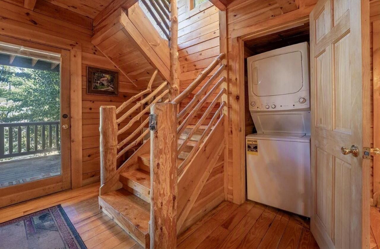A wooden staircase leading to a deck, a washing machine, and a door with a brass handle.