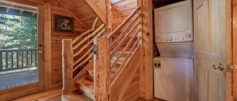 A wooden staircase leading to a deck, a washing machine, and a door with a brass handle.