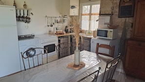 Una cucina con tavolo e sedie, lavatrice, fornello e forno a microonde.