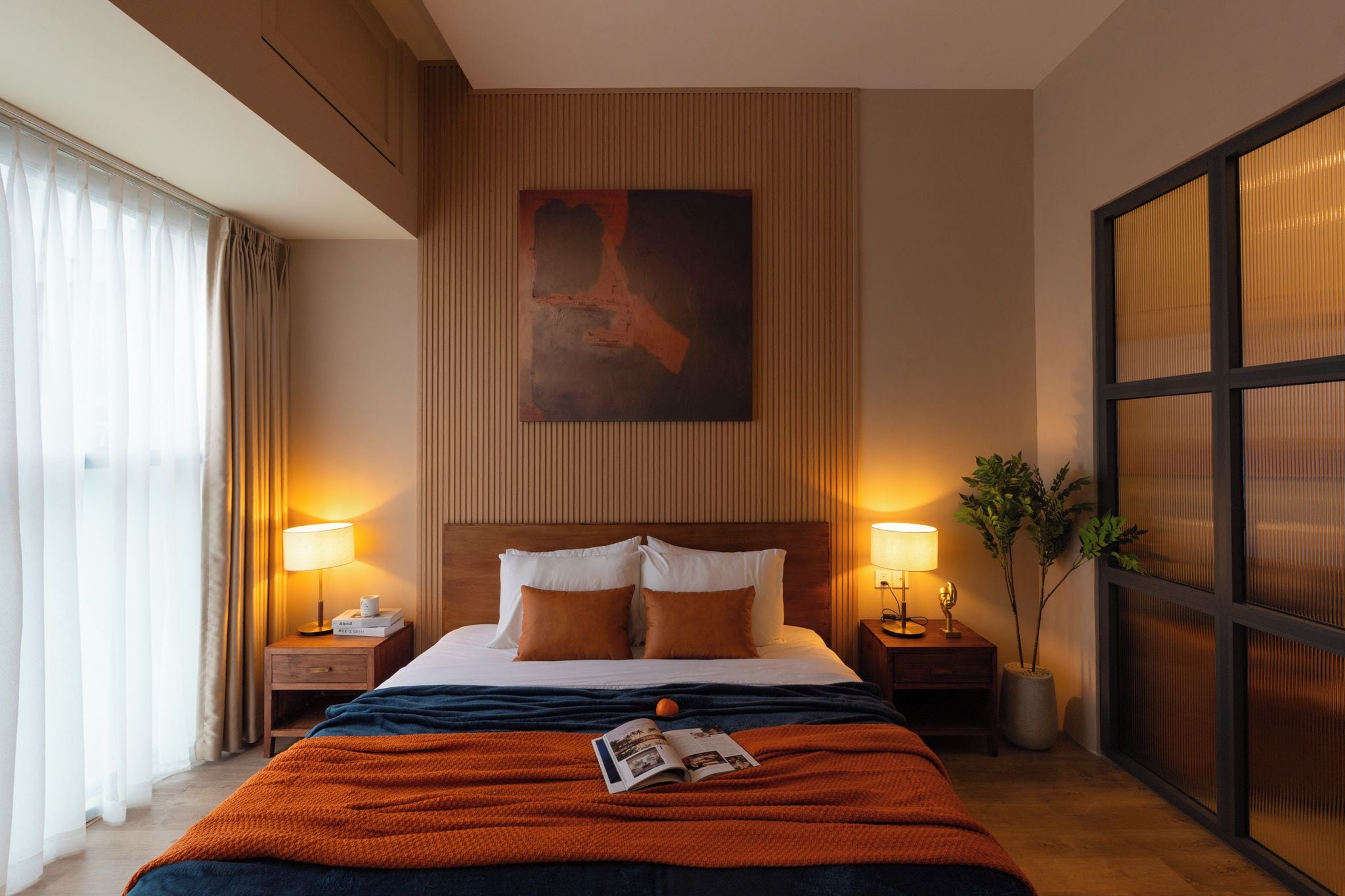 Une chambre d’hôtel avec un grand lit, deux tables de chevet avec des lampes, une grande fenêtre avec des rideaux et un tableau au mur.