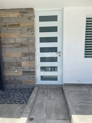 A white door with multiple glass panels, a wooden wall to the left, and a tiled floor. - Bucketlist Private Beach Villa Walk Beach-2ndFloor (San Juan)