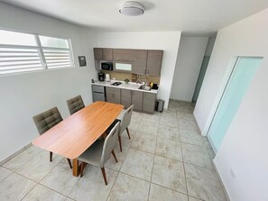 A modern kitchen with a dining area, featuring a wooden table and chairs, a microwave, and a sink. - Bucketlist Private Beach Villa Walk Beach-2ndFloor (San Juan)