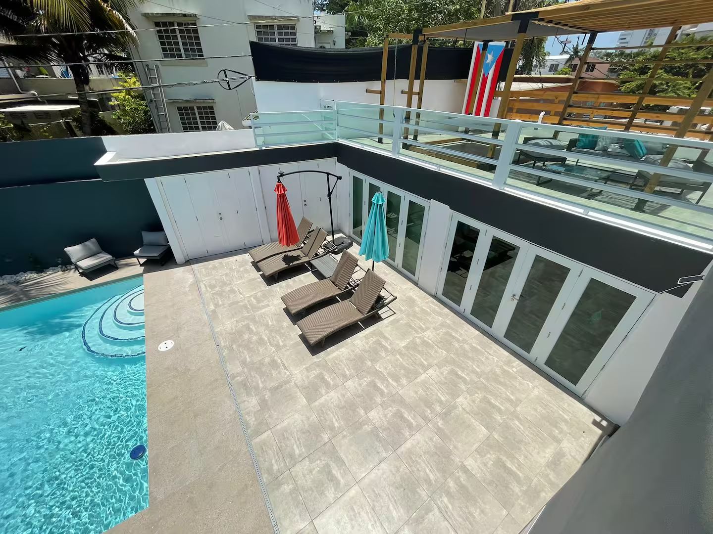 A rooftop pool area with sun loungers and a glass balustrade.