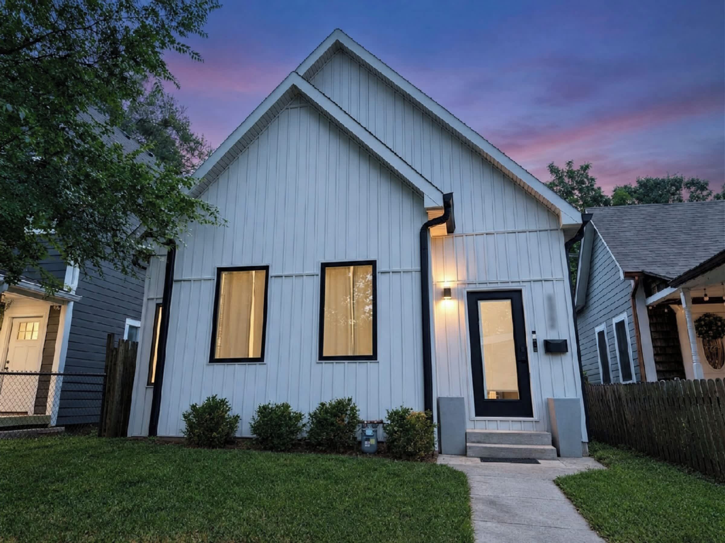 A modern single-story house with a gabled roof, a front porch, and a well-maintained lawn.