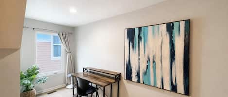 A room with a desk, chair, and a large abstract painting on the wall.
