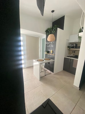A modern kitchen with a dining area, a chalkboard with writing, and a hanging plant. - Lovely 1 bedroom apartment close to everything SJ (San Juan)