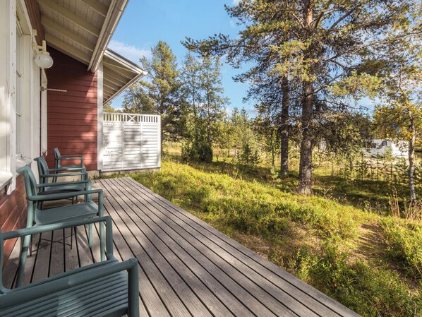 A wooden deck with outdoor furniture, a covered porch, and a natural landscape with trees and bushes. - Lapinhelmi by Interhome (Inari)