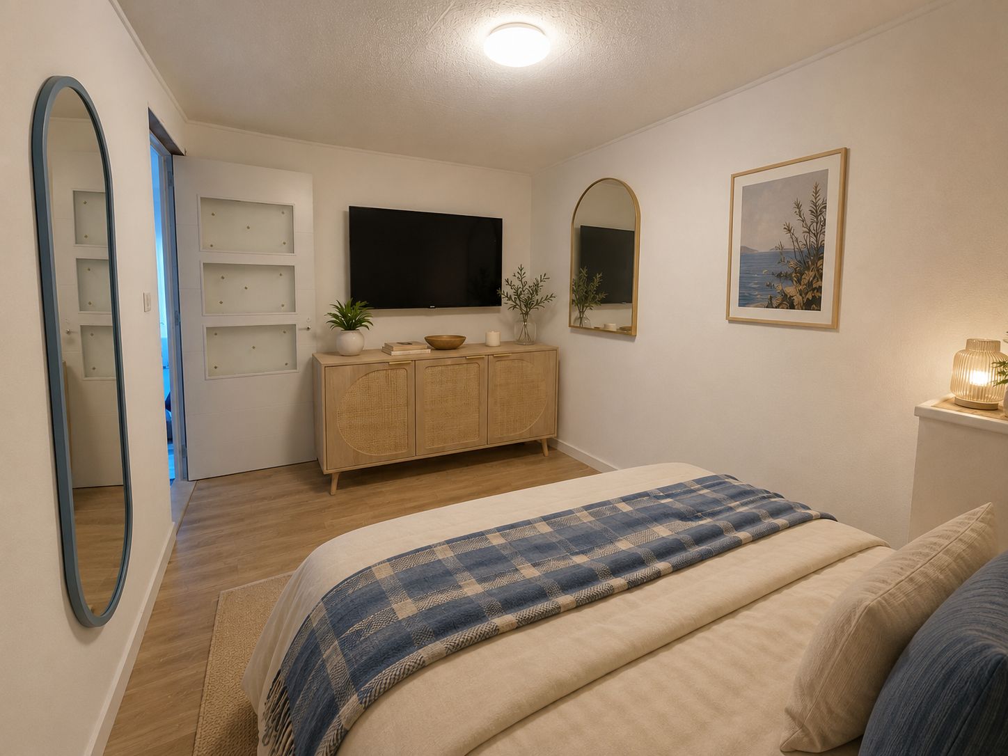 Une chambre à coucher comprenant un lit, une télévision, un miroir, une armoire et un tableau encadré accroché au mur.